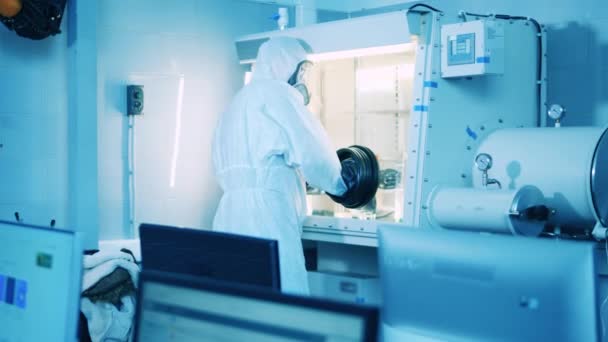 A man in a splash suit is working with a vacuum cabinet in the lab — Stock Video