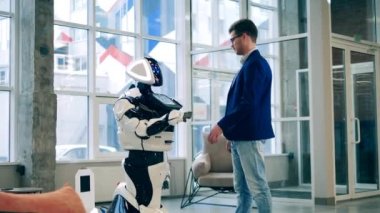 Takım elbiseli bir adam ve bir cyborg temas halindeler.