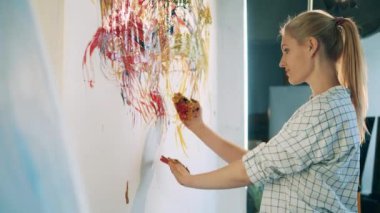 Bir kadın duvara resim yapmak için iki elini kullanıyor.