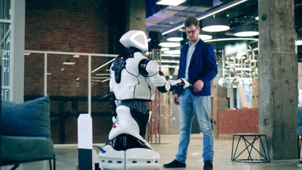 Un hombre en un traje de negocios está tocando robots mano — Vídeo de stock