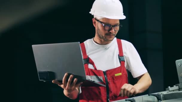 Ingegnere specialista con un computer portatile sta osservando un trasportatore — Video Stock