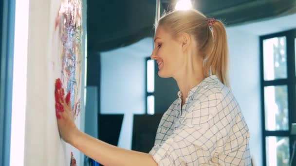 Blond kvinna är lycklig medan hon målar med händerna — Stockvideo