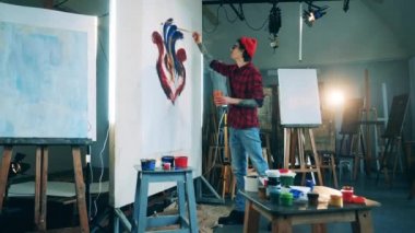 Sanat stüdyosunda bir adam güzel bir resim çiziyor.