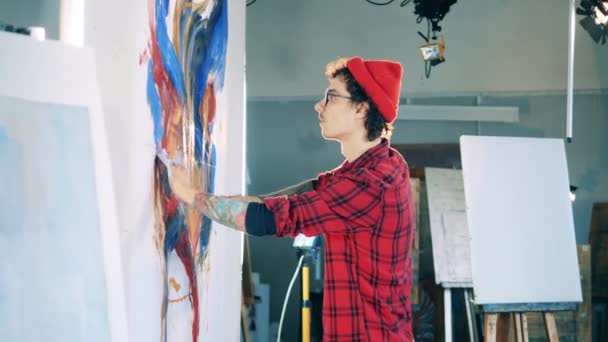 Jongeman schildert een schilderij met blote handen — Stockvideo