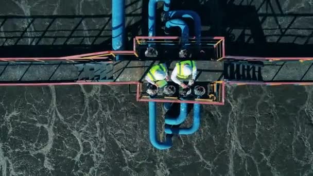 Vista dall'alto di due lavoratori in piedi sulla costruzione di depurazione — Video Stock
