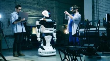 Gelecekçi teknoloji konsepti. Fabrika işçileri robotu test etmek için VR kullanıyor. Gelecek, yenilik, bilim, robot kavramı.
