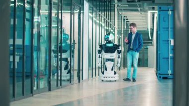 Bir adam ve bir robot koridorda ilerliyorlar.