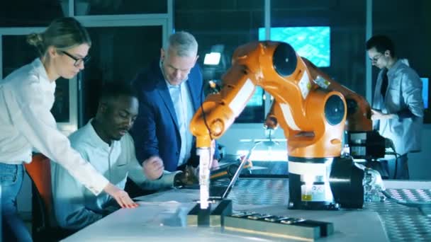 A kutatók egy csoportja egy robotmechanizmussal kísérletezik. Professzionális mérnökök innovatív berendezésekkel, csapatmunkával. — Stock videók