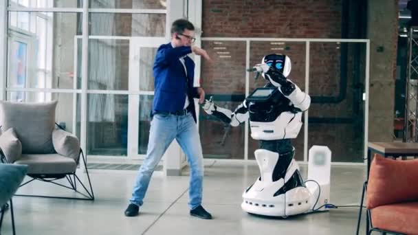 El hombre de negocios está enseñando a un cyborg a bailar. Concepto de comunicación humana y robótica. — Vídeo de stock