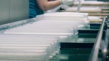 Plastik bardaklar bir fabrika işçisi tarafından selofana sarılıyor.