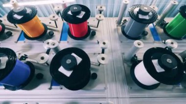 Kablo fabrikasında bir sürü renkli dönen makaralar var.