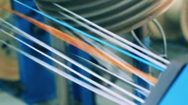 Birçok küçük renkli kablolar bir makaradan sarkıyor.