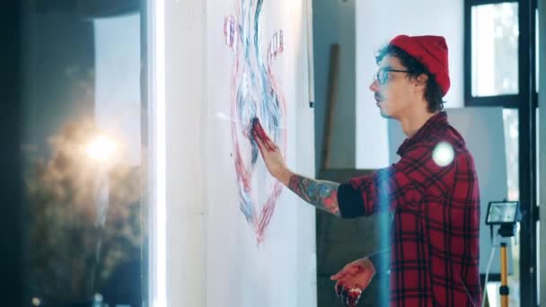 Tatuado homem está pintando um quadro com as próprias mãos — Vídeo de Stock