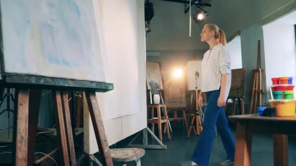 Kreacja, inspiracja. Blondynka dotyka ogromnego białego płótna w studiu. Kreatywne hobby, koncepcja stworzenia dzieła sztuki. — Wideo stockowe