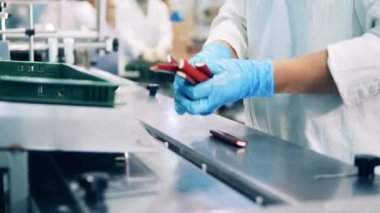 Factory worker is assisting in conveyor transportation of candies
