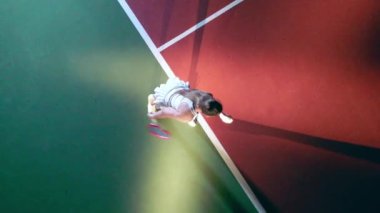 Sahada tenis oynarken bir bayan top servis ediyor.