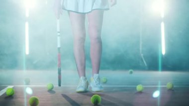 Lower body of an athletic lady carrying a tennis racket