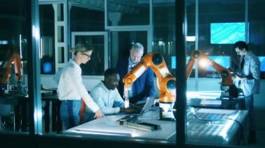 Group of science workers, developers work with robotic arm.