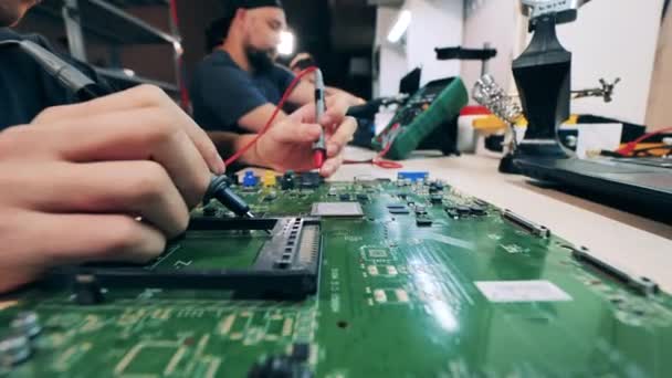 Technician testing laptop motherboard with multimeter — 图库视频影像