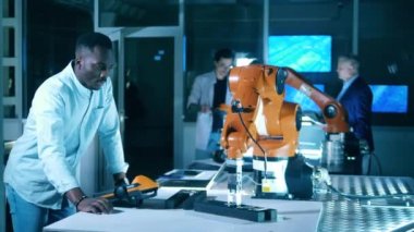 Diverse team of development engineers working with robotic mechanism in a modern laboratory.