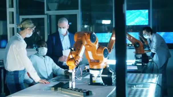 Science workers in face masks working with robotic arms. — Stockvideo