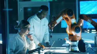 Bilim laboratuarında çalışan iki araştırmacı bir robot üzerinde çalışıyorlar, endüstriyel robot..
