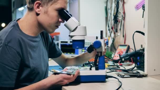 Reparationsspecialist tittar på systemkort genom mikroskop — Stockvideo