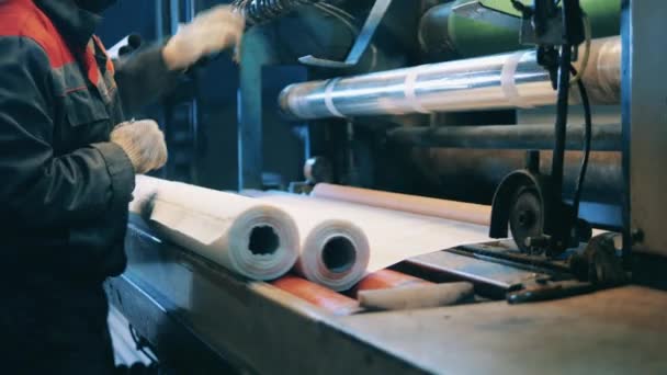 Fabrieksarbeider die een papierrolmachine bedient — Stockvideo