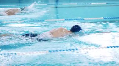 Sporcular yüzme havuzunda kurbağalama yüzer