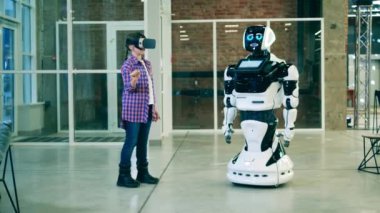 Küçük kız, VR kulaklık kullanan gelecekçi bir robot kullanıyor. Robot bilimi, teknoloji, yenilik kavramı.