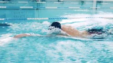 Profesyonel atlet havuzda kurbağalama vuruşu yapıyor.