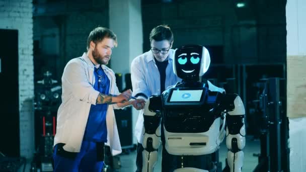 Specjaliści naprawiają futurystycznego robota w laboratorium. Koncepcja sztucznej inteligencji. — Wideo stockowe