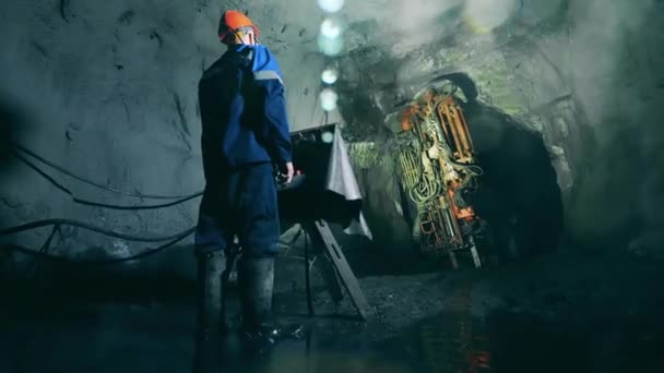 Desenvolvimento subterrâneo, extração subterrânea, operações de mineração subterrânea. Máquina aborrecida está sendo gerenciada por um trabalhador de mina — Vídeo de Stock