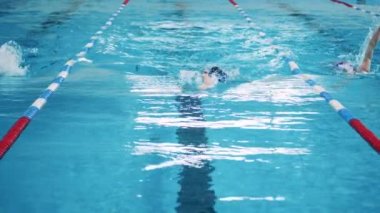 Ön planda kurbağalama yüzen bir adamın yavaş hareketi.