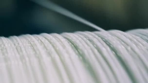 Close up shot of a white-colored power cable unwinding from a spool — Stock Video