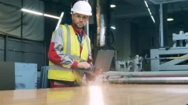 Dizüstü bilgisayarda mühendislik uzmanı fabrika makinelerini izliyor.