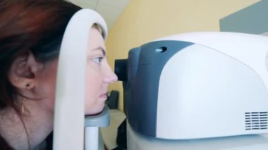 Bir kadın görme duyusunu kontrol ettirmek için makineye bakıyor.