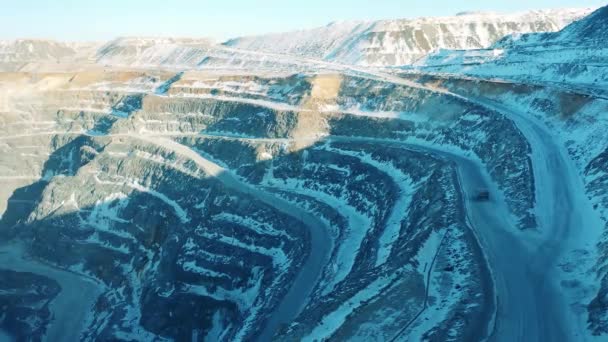 Vista superior de uma mina a céu aberto com um camião a atravessá-la. Pedreira, mineração a céu aberto, conceito de extração de minério. — Vídeo de Stock