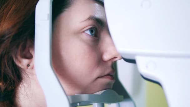 한 여성 이 의료 기기를 통해 자신의 눈을 검사받고 있습니다 — 비디오