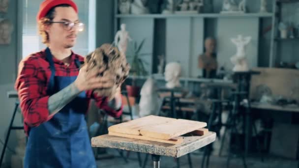 Male artist is putting down a piece of clay and starts working with it. Art concept, creative studio interior. Creativity, design, craft work concept. — Stock Video