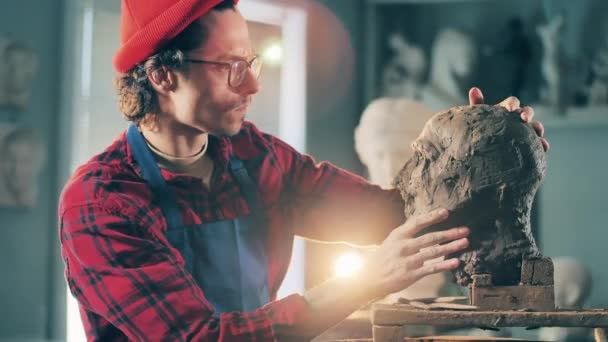 한 남자가 자신이 만든 점토 조각품을 보고 있습니다. 창의력, 설계, 공예 작업 개념. — 비디오