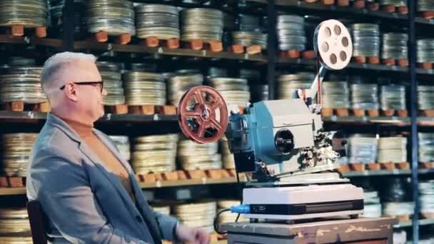 Arkivspecialisten skrattar bredvid den antika filmprojektorn — Stockvideo