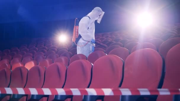 Trabajador rocía desinfectantes dentro de un cine — Vídeo de stock