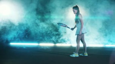 Bayan oyuncu raketle tenis topuyla hokkabazlık yapıyor.