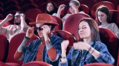 Film izlemek, zaman geçirmek. Sinemada insanlar gözlük takıyor.