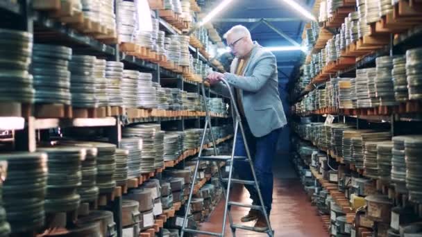 O especialista em arquivos está à procura de um caso de filme nas prateleiras. — Vídeo de Stock