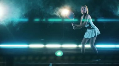 Kadın oyuncu maç sırasında tenis topuna vuruyor