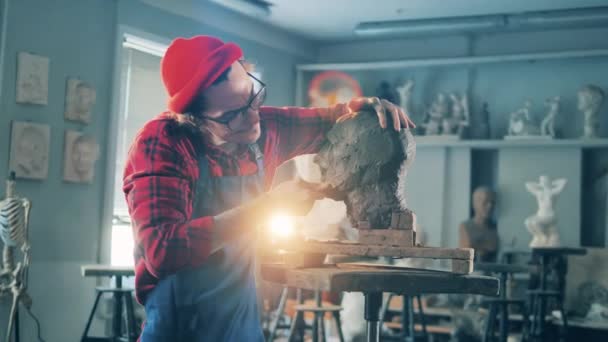 Inspiration, Kreativität, Design, Vorstellungskraft. Männlicher Bildhauer glättet Tonoberfläche einer Kopfskulptur — Stockvideo