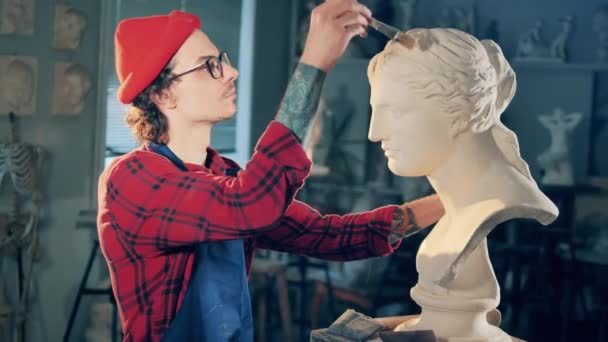 Muž sochař kartáčuje bílou sádrovcovou bustu — Stock video