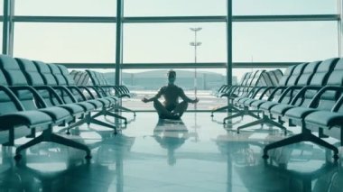 Yüz maskeli bir kadın kalkış salonunda meditasyon yapıyor.